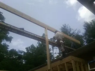 Carpenter setting a ridge beam over a new addition frame — Ice Dam Removal by Roofing Brothers in Westland