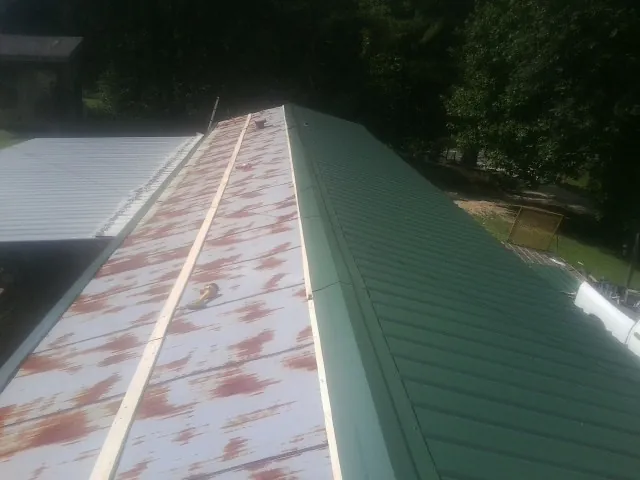 Old rusted panels beside newly installed green metal roofing — Wind Damage Roof Repair by Roofing Brothers in Westland