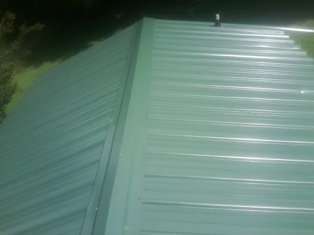 New green metal panels meeting at the ridge of a roof — Flat Roof Repair work by our crew in Westland
