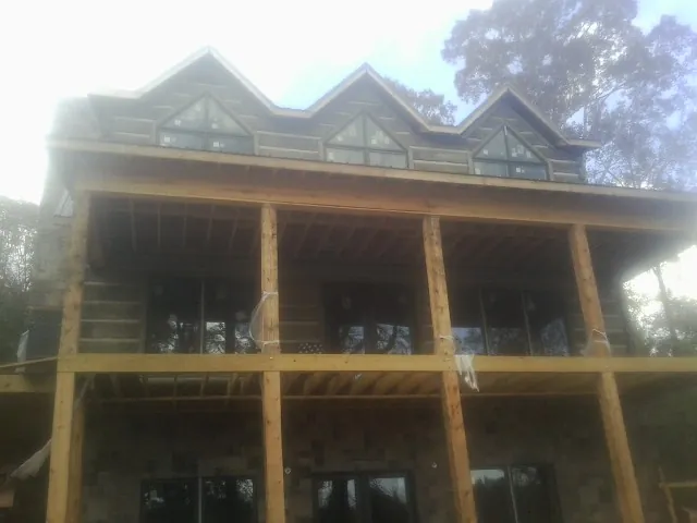 Dormers and porch framing on a large log home under construction — Roof Coating work by our crew in Westland