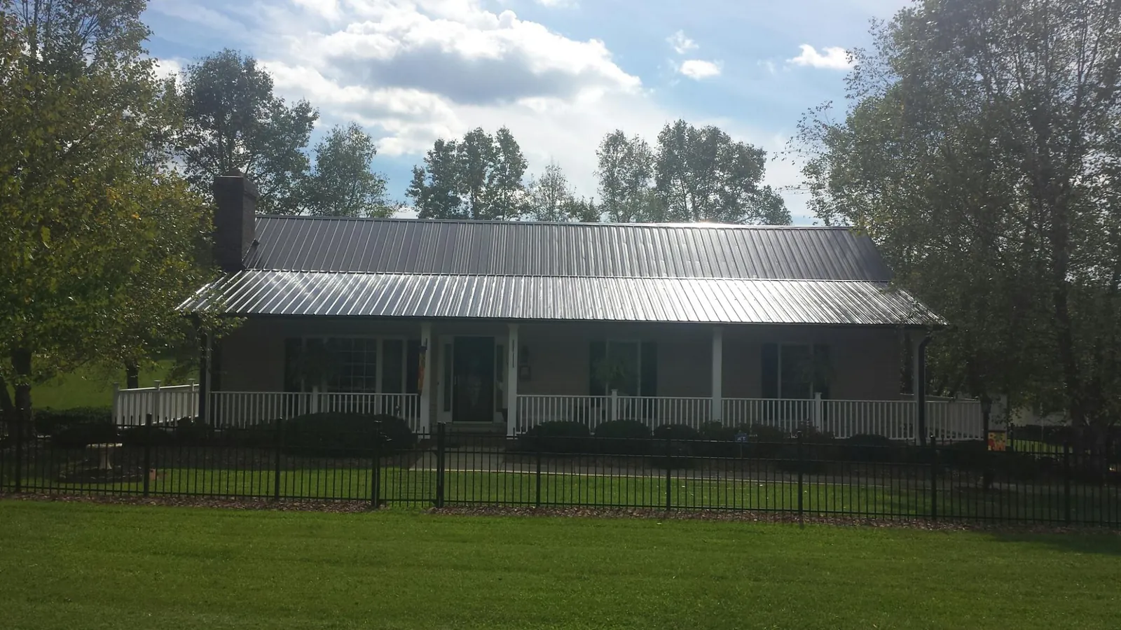 Gray metal roof on a brick ranch with a full width front porch — Gutter Guard Installation work by our crew in Westland