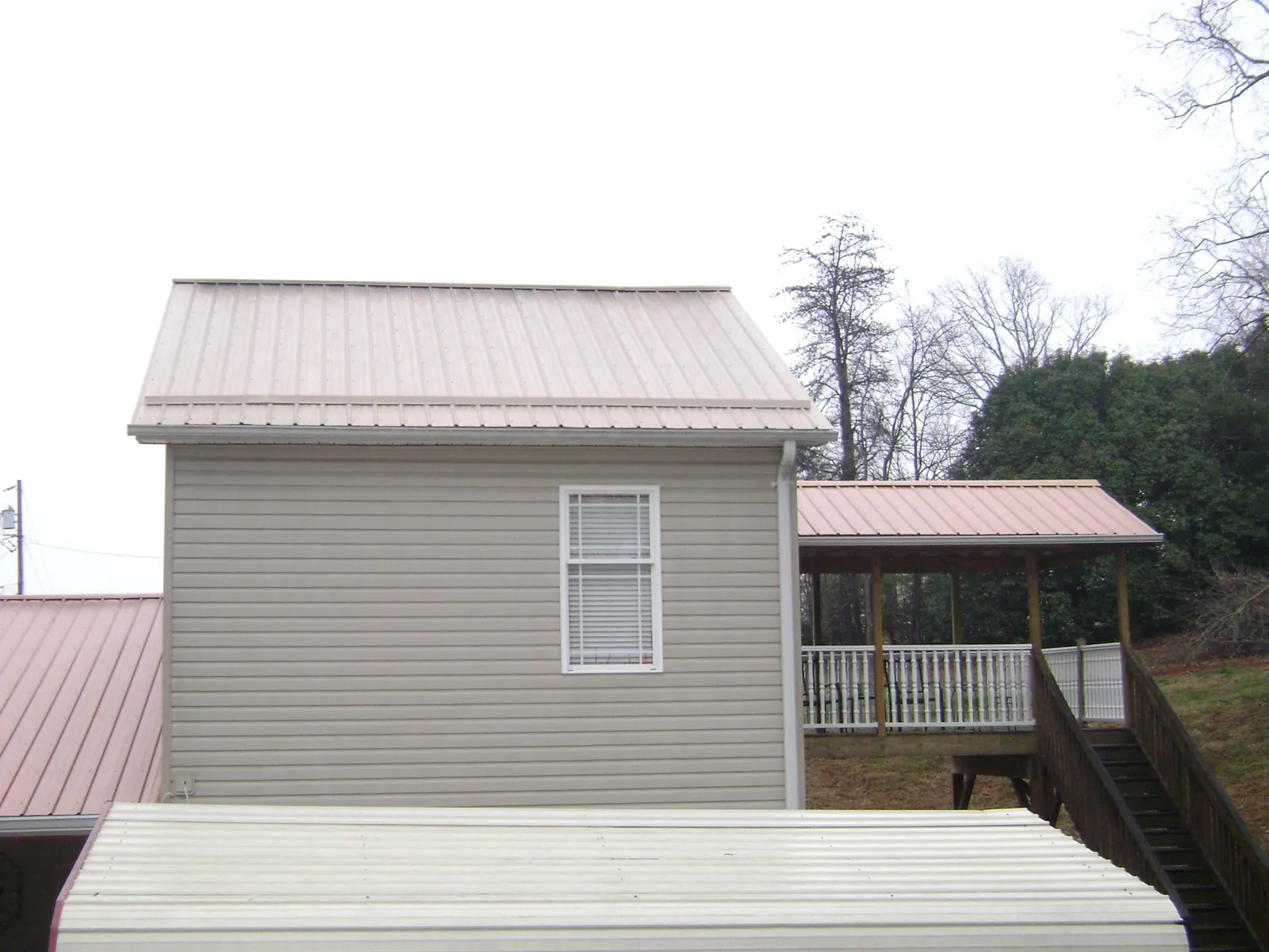 Tan metal roofs on a two story addition and attached porch, from a Roof Replacement job in Westland