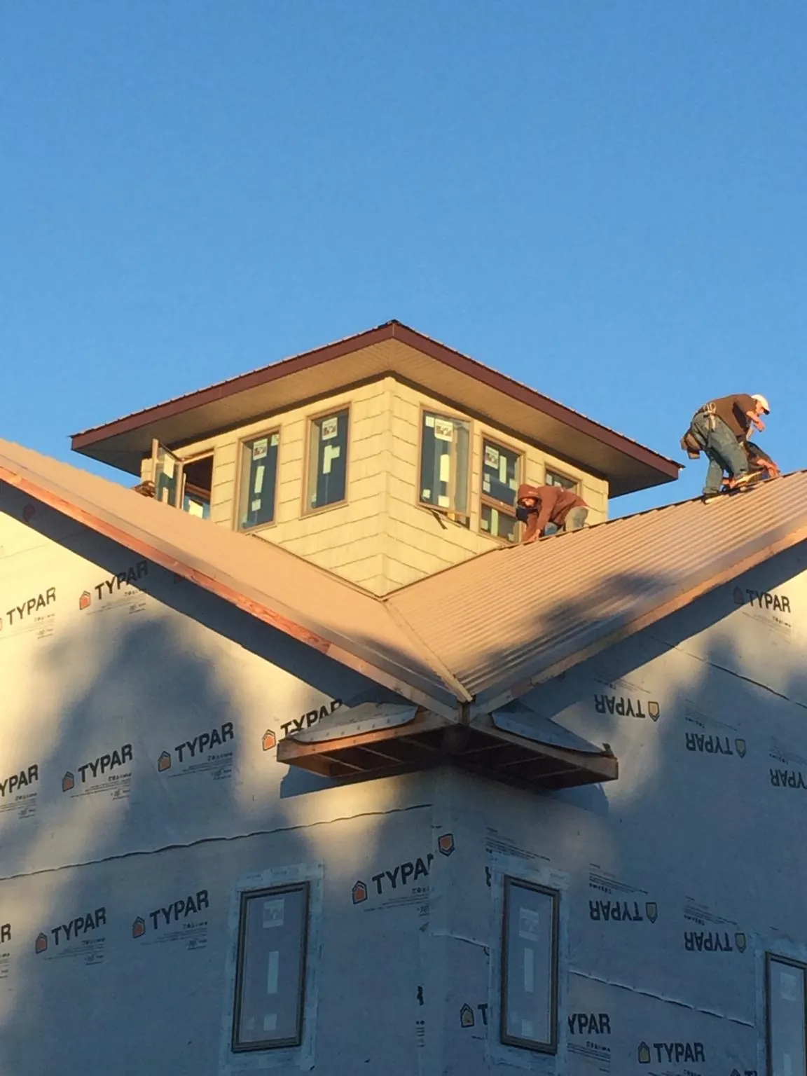 Roofers working around a rooftop cupola on a new metal roof at sunset — Roof Waterproofing in Westland by Roofing Brothers